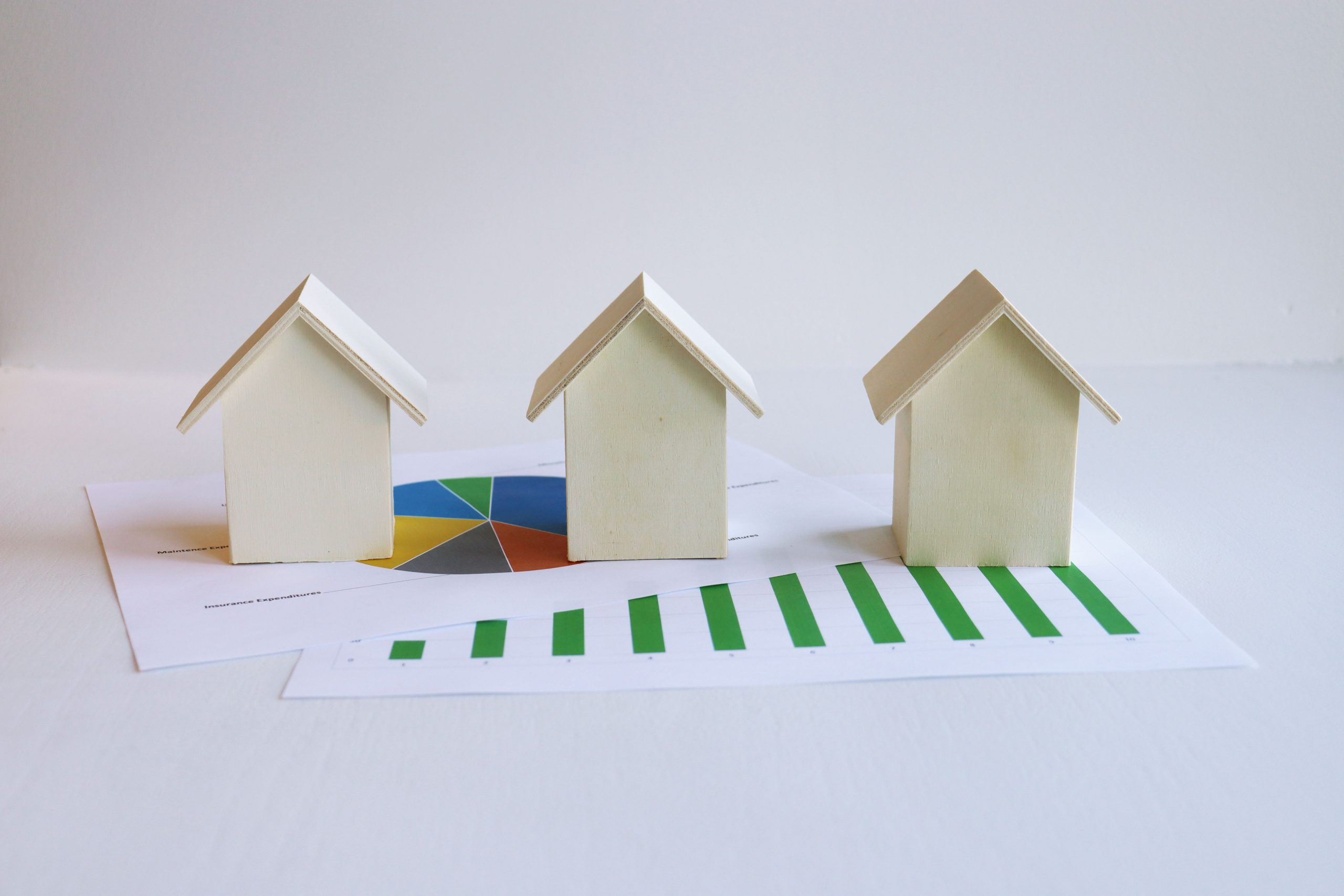 Wooden model houses on graphs depict real estate market analysis and trends.